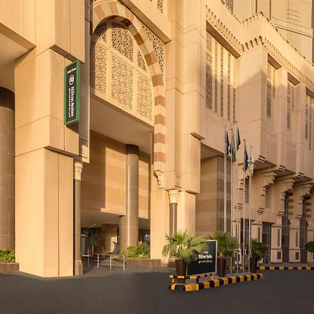 Hilton Suites Jabal Omar Makkah Meca Exterior foto The photo shows a modern building with a distinctive architectural style, featuring large, light-colored stone facades. The entrance is prominent, with a wide, inviting pathway leading up to it. To the left, there is a sign that appears to indicate t